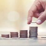 Hand stacking coins in rising levels to represent a CD ladder and growing short-term savings