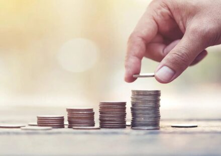 Hand stacking coins in rising levels to represent a CD ladder and growing short-term savings