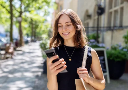 A consumer reviewing a bank statement on a smartphone showing checking account deposit balance and fee adjustments